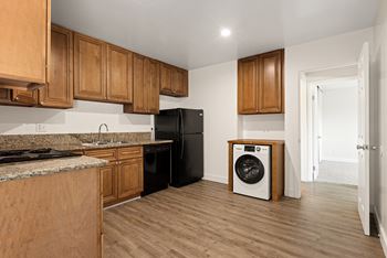 a kitchen with wood cabinets and a black refrigerator and a washing machine